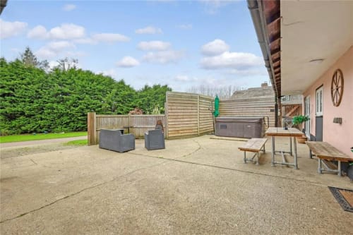 Spacious patio at The Stables, Blackbrook Cottages in Colchester, with seating, picnic tables, and landscaped garden views