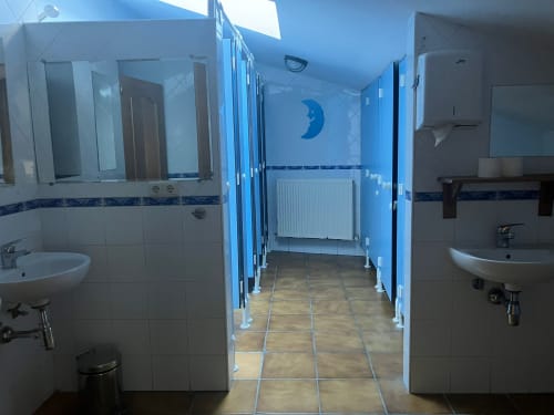 Shared bathroom at Posada de Ollo hotel with blue-tiled walls, sinks, and moon decoration