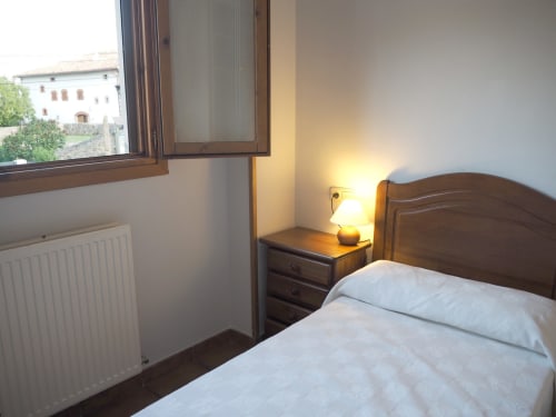 Cozy double bedroom at Posada de Ollo with wooden furniture, bedside lamp, and mountain views from the window