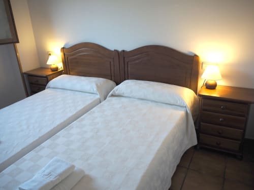 Twin beds with wooden headboards and bedside lamps in Gaztelu room at Posada de Ollo hotel, Spain
