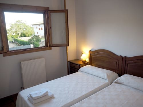 Bright bedroom at Posada de Ollo with twin beds, wooden headboard, and mountain view window in Spanish countryside