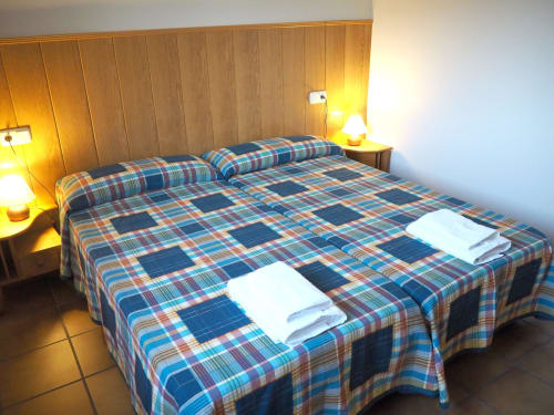 Cozy double bedroom at Posada de Ollo with plaid bedding, wooden headboard, and warm lighting in Spain