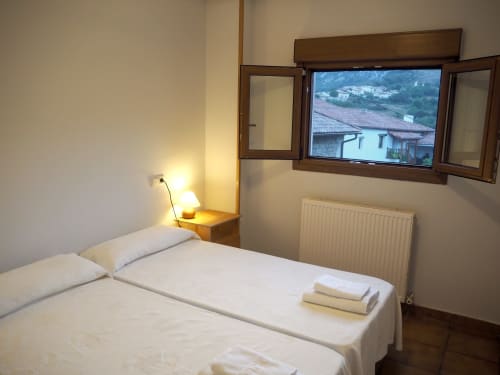 Cozy hotel room at Posada de Ollo with twin beds, mountain views through window, bedside lamp, radiator, and wooden