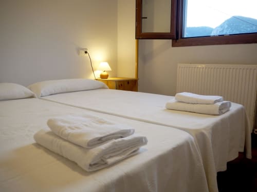 Clean twin beds with fresh towels at Posada de Ollo hotel room with mountain view in Spain