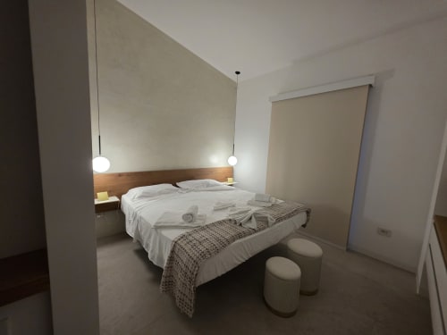 Modern bedroom at eDomos Villagì Luxury Villa in Cagliari with double bed, pendant lights, and sea view roller blinds