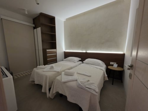 Modern bedroom at eDomos Villagì Luxury Villa in Cagliari with twin beds, dark headboard, and backlit wall panel