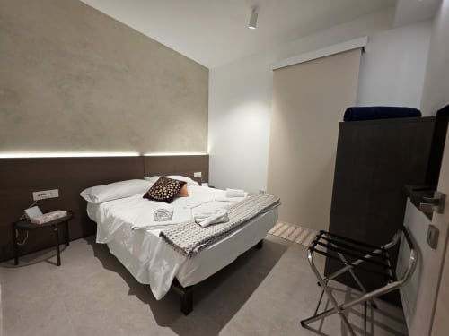 Modern bedroom at eDomos Villagì Luxury Villa in Cagliari with white bedding, dark wood headboard, and contemporary