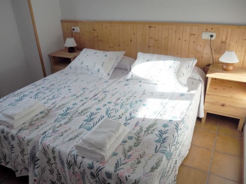 Bright double bedroom at Posada de Ollo with wooden headboard, floral bedding, and mountain views in Beriáin, Spain