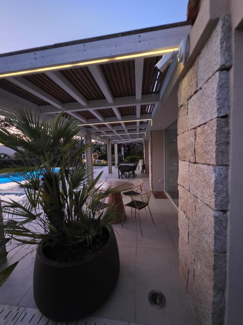 Modern pergola with LED lighting over patio area at Villagì Luxury Villa in Cagliari, overlooking pool