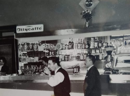 Interno vintage del bar dell'Albergo Al Cinghiale a Guspini con baristi e scaffali di bottiglie