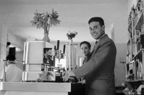 Uomo al bancone del bar con macchina da caffè vintage all'Albergo Al Cinghiale, Guspini Italia