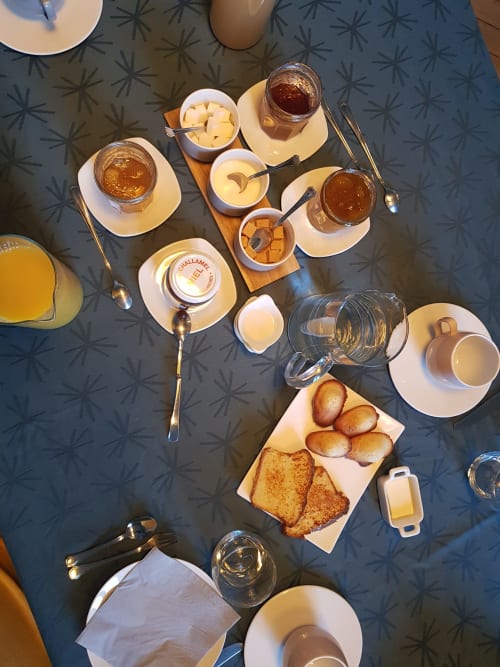 Overhead view of a French breakfast spread at Domaine de l'Oie Rouge B&B, featuring pastries, jams, butter, and beverages on