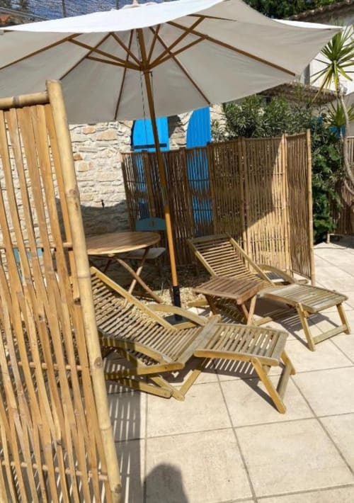 Zone de détente ombragée au Patio aux Oiseaux à La Ciotat avec transats en bois et parasol