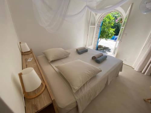 Chambre minimaliste lumineuse au Patio aux Oiseaux avec lits jumeaux, vue sur le jardin par portes ouvertes et mobilier épuré