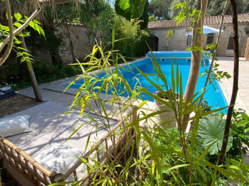 Piscine rectangulaire bleue avec chaises longues, verdure luxuriante et bâtiments en pierre à Le Patio aux Oiseaux, La Ciotat