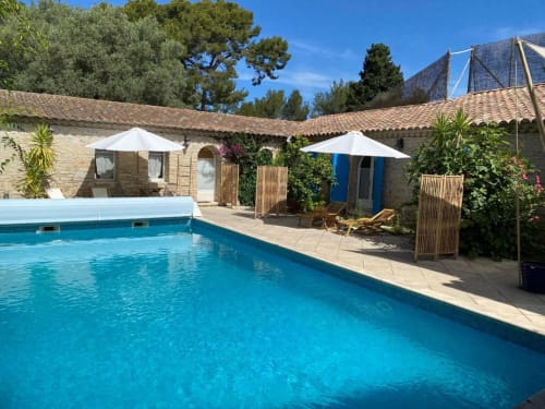 La Cour aux Oiseaux avec piscine à La Ciotat : bassin bleu, bâtiments en pierre et paysage méditerranéen