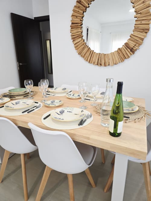 Mesa de comedor elegantemente dispuesta para varios huéspedes en el apartamento Ona vacaciones de Gandía, con botella de vino y servicios de mesa