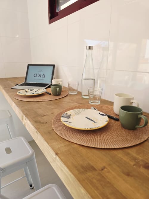 Mesa de comedor de madera en apartamento Ona vacaciones Gandía con portátil, cubiertos, botella de agua y tazas de café