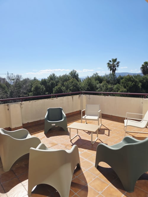 Terraza en azotea con mobiliario moderno en apartamento Ona Vacaciones de Gandía, con vistas a árboles y montañas