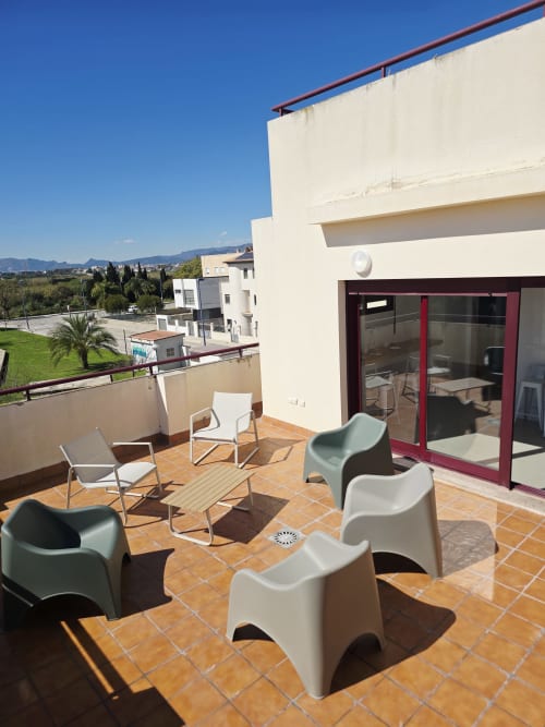 Terraza soleada en apartamento Ona Vacaciones Gandía con mobiliario moderno, baldosas de terracota y vistas a la montaña