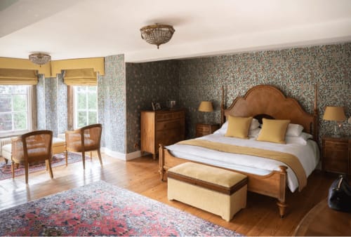 Luxuriöses Schlafzimmer in den Florence Nightingale Suites in Derbyshire mit Holzbett, gemusterter Tapete und zeitgenössischen Möbeln
