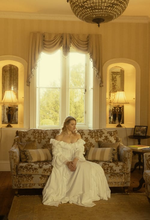 Frau in weißem Kleid auf ornamentalem Sofa im eleganten Wohnzimmer des Florence Nightingale Suites in Holloway