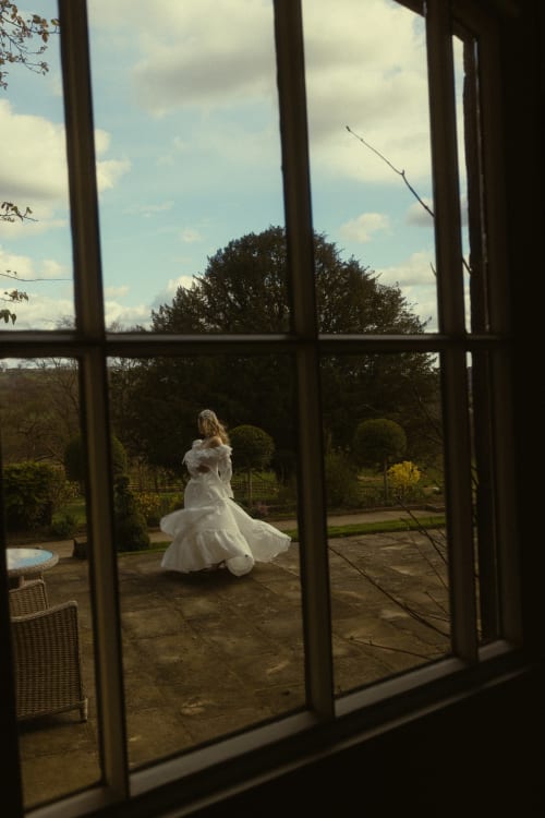 Frau im weißen Kleid, die im Garten der Florence Nightingale Suites in Derbyshire wirbelt