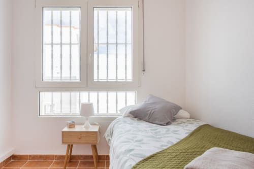 Dormitorio luminoso con dos camas individuales, mesilla de madera y amplios ventanales con vistas a Pinatar en Villa ALROGA