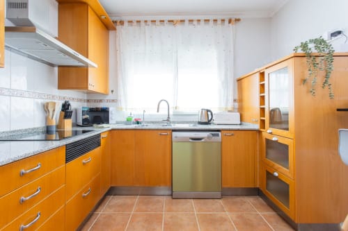 Cocina moderna con muebles de madera dorada, encimeras de granito y electrodomésticos de acero inoxidable en Villa ALROGA, San Pedro del