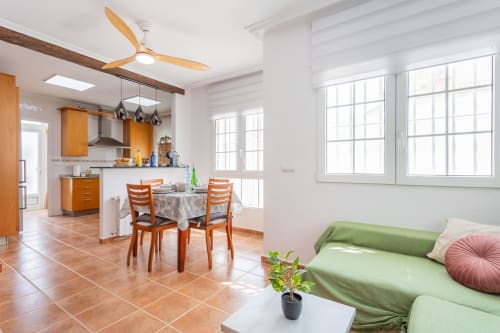 Luminosa cocina y comedor abiertos en Villa ALROGA, San Pedro del Pinatar, con sillas de madera naranjas y baldosas de terracota