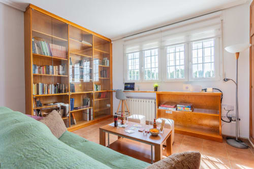 Luminoso salón con sofá verde, librerías de madera, grandes ventanales y escritorio en Villa ALROGA, San Pedro del Pinatar