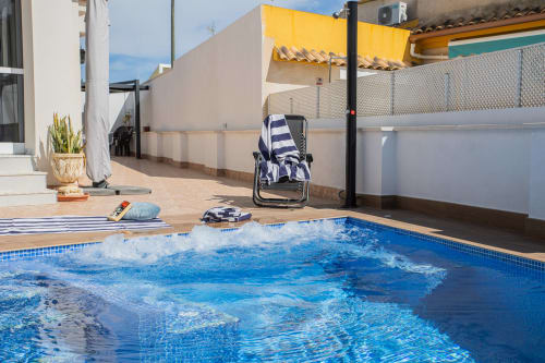 Piscina privada con azulejos azules en Villa ALROGA en San Pedro del Pinatar, con tumbonas y sillas de playa