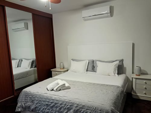 Modern bedroom at Villa Supranee with sea view, white bedding, mirrored wardrobe, and air conditioning in Câmara de Lobos