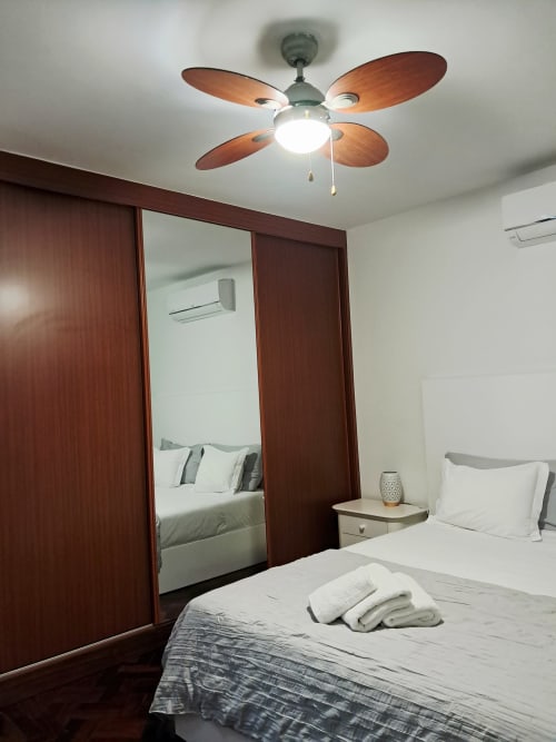 Modern bedroom at Villa Supranee with wooden ceiling fan, mirrored wardrobe, and sea view in Câmara da Lobos