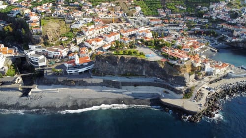 Aerial view of Villa Supranee in Câmara da Lobos, Portugal with coastal beach, rocky cliffs and seaside town nestled on