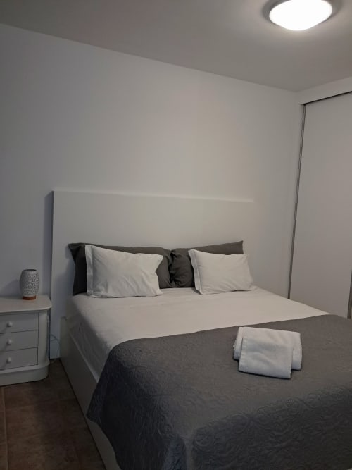 Modern bedroom at Villa Supranee in Câmara de Lobos with queen bed, white bedding, dark throw, nightstand, and ceiling light