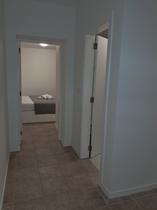 Villa Supranee apartment hallway with brown tile flooring, white walls, bedroom with bed visible through doorway, Câmara da