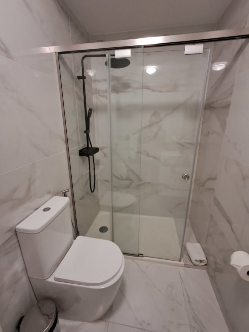 Modern bathroom at Villa Supranee with marble tiles, glass shower enclosure, and white toilet in Câmara da Lobos