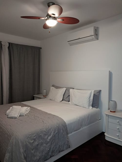 Modern bedroom at Villa Supranee with queen bed, ceiling fan, AC unit, dark curtains, and sea view in Câmara da Lobos