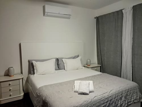 Modern bedroom at Villa Supranee with sea view, white headboard bed, gray curtains, air conditioning, and minimalist decor in