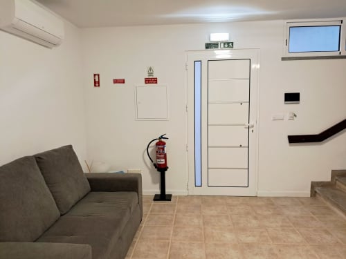 Aldeia Supranee apartment lounge with gray sofa, fire extinguisher, and white door in Câmara da Lobos