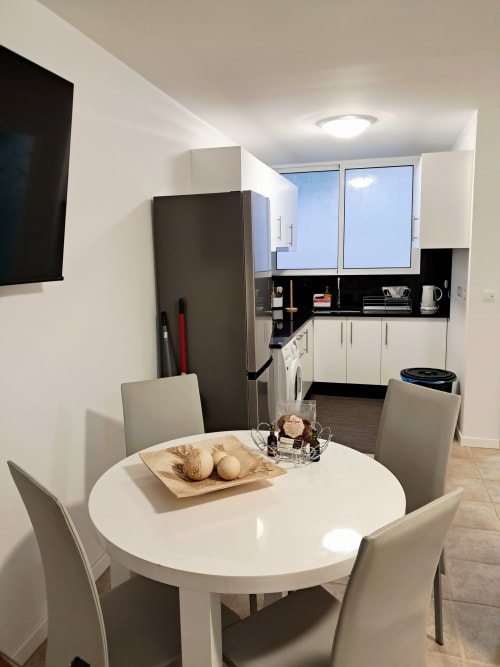 Modern dining area with round white table and beige chairs in Villa Supranee apartment, Câmara de Lobos, featuring