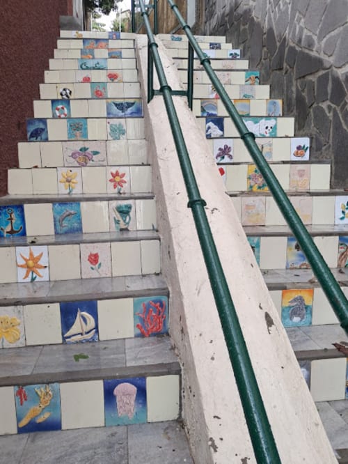 Degraus de azulejos pintados à mão na Villa Supranee em Câmara de Lobos, Portugal, decorados com obras de arte coloridas com temática marinha e verde