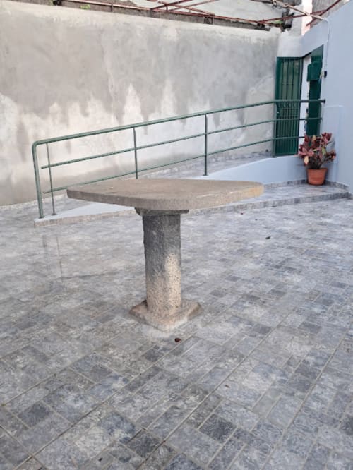 Mesa de pedra no terraço da Villa Supranee em Câmara de Lobos com grade verde e vista para o mar