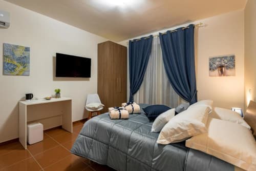 Mistral Room at Torre dei Venti in Ceccano featuring a bed with gray bedding, flat-screen TV, wooden wardrobe, and blue