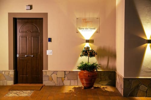 Corridoio d'ingresso della Torre dei Venti a Ceccano con porta in legno, vaso in terracotta e illuminazione calda