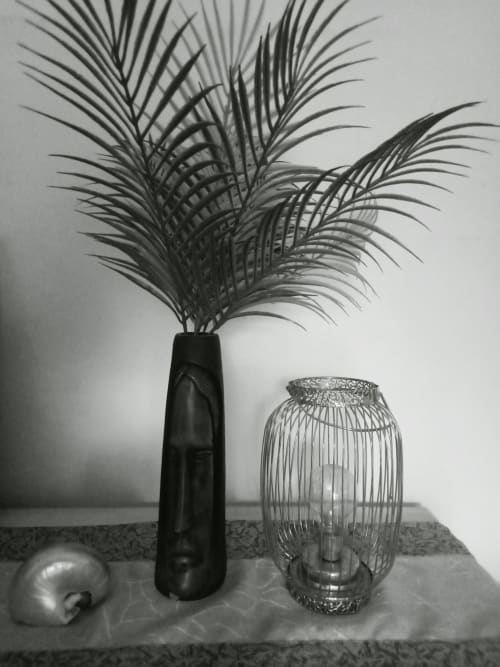 Allestimento minimalista al Borgo Luce con vaso nero, fronde di palma e lanterna decorativa presso il B&B Francavilla Marittima.