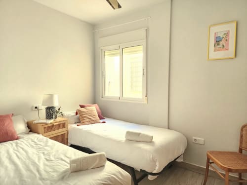 Dormitorio luminoso en BAKIT HOUSE en Águilas con camas gemelas, ventana, lámpara de noche y silla de madera