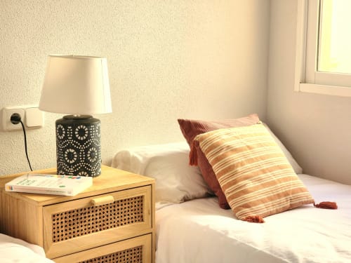 Acogedora habitación en BAKIT HOUSE en Águilas con mesita de noche de madera, lámpara decorativa, almohadas rayas y vista a la ciudad