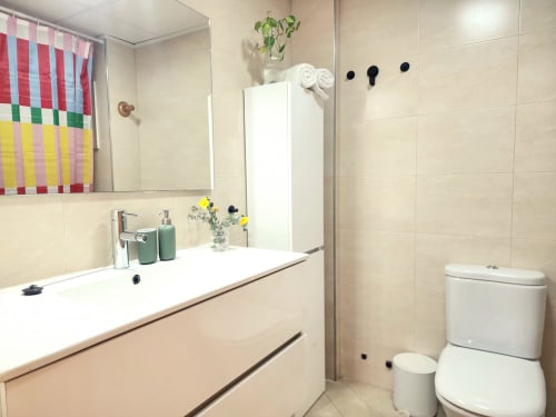 Baño moderno en BAKIT HOUSE en Águilas con lavabo blanco, inodoro, cortina de ducha colorida y paredes de azulejos